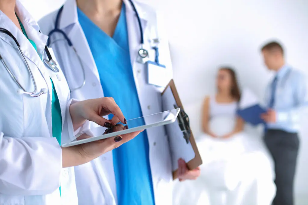 Clinicians on tablet near patient