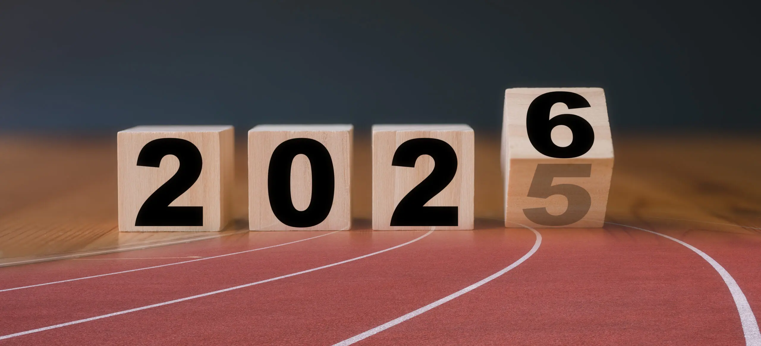 A set of wooden blocks showing the change from 2025 to 2026 atop a track