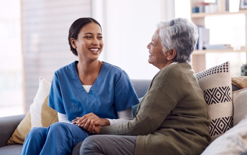 Healthcare professional talking to patient on sofa